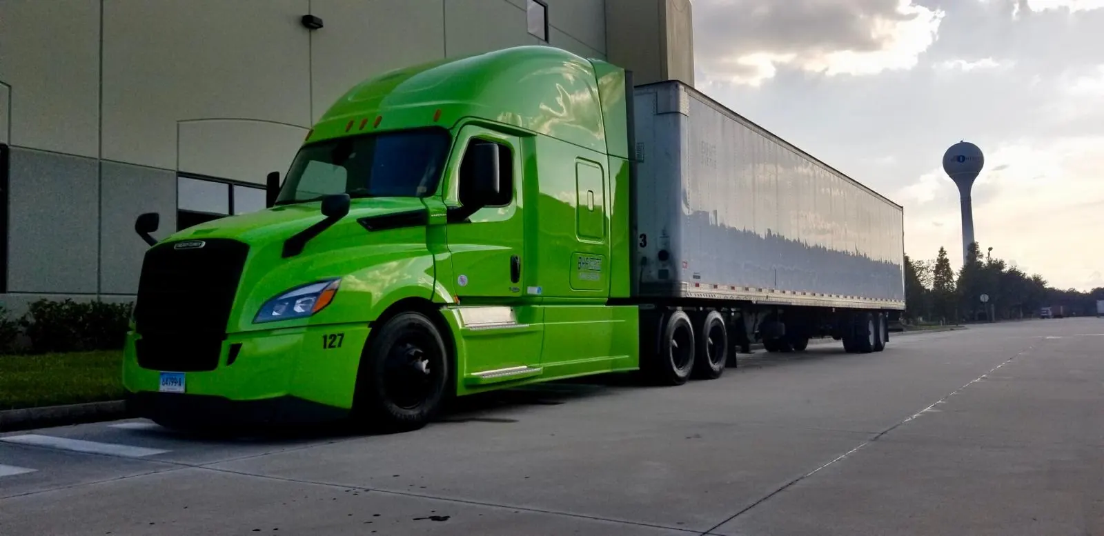 Green truck with trailer at a loading dock